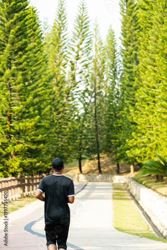 a man jogging along a paved path in Taman Saujana Hijau, a popular 41-hectare recreational park located in Putrajaya, Malaysia