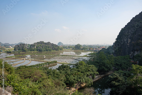  panoramic wide-angle shot overlooking a network of flooded rice fields and winding dirt paths in the Tam Coc region
