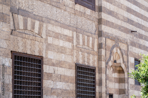 View of the intricate Mamluk architecture of Al Ghuri Dome featuring ablaq masonry, Arabic calligraphy, and ornate window grilles, Cairo, Egypt.