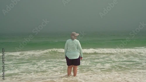 Slow Motion Plus size woman walking towards ocean on a foggy day on in Pesacola Florida