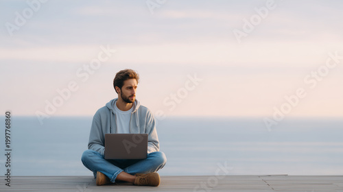Man working on laptop by the ocean. Digital nomad lifestyle, remote work, and technology concept for freelancer business in a peaceful outdoor setting with copy space.