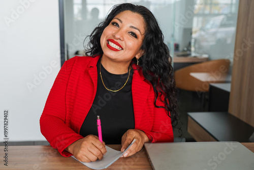 Latin woman car sales agent writing at desk