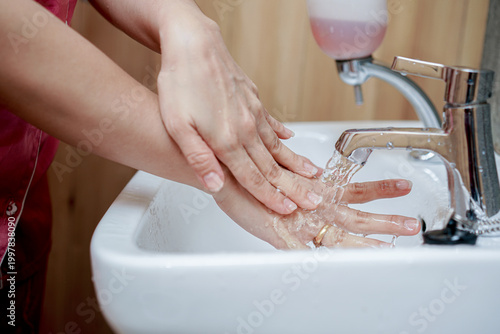 Washing hands thoroughly with water flow at sink to prevent bacteria