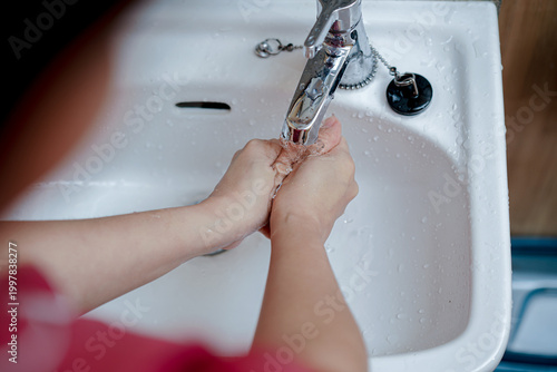 Human hands rubbing together under running water for hygiene and cleanliness