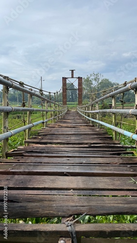 Rustic Suspension Bridge Over Water with Wooden Structure and Scenic Natural Landscape View