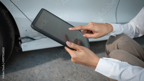 Bild auf Leinwand Hands of an auto inspector holding a tablet, documenting a dent and scratches on a white car door, close-up at a repair shop, vehicle damage assessment and insurance claim concept