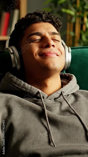 Young Man Relaxing on Green Sofa Listening to Music with Headphones