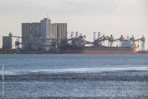 View of a large bulk carrier cargo ship docked at an industrial terminal with grain silos and loading cranes in Lisbon, Lisbon, Portugal.