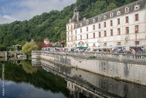 Vibrant outdoor market along the Dronne river with Benedictine Abbey, Brantome