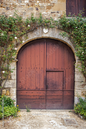 Historic Arched Wooden Door with Roses in Saint-Jean-de-Cole, France