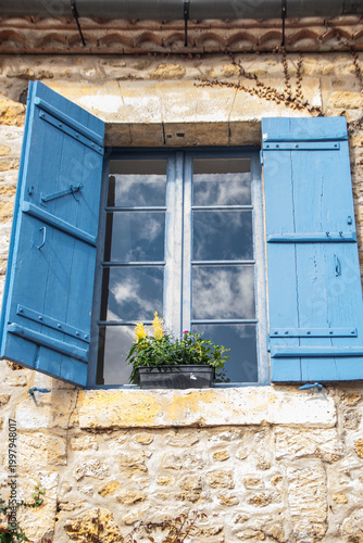 Traditional French window with blue shutters and sky reflection in Saint-Jean-de-Cole