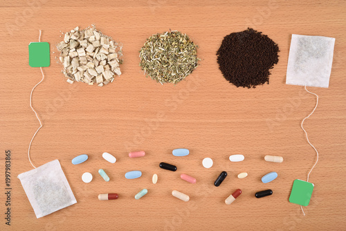 Assortment of dry teas, capsules, tablets and tea bags on the wooden table. Copy space. Top view. What to choose: Medicines or herbal treatment?