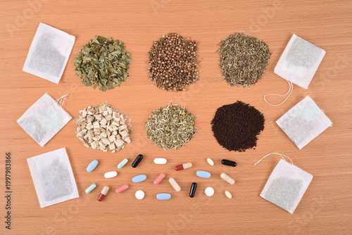 Assortment of dry teas, capsules, tablets and tea bags on the wooden table. Top view. What to choose: Medicines or herbal treatment?

