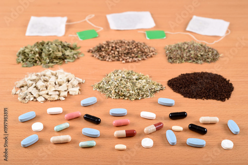 Assortment of capsules, tablets, dry teas and tea bags on the wooden table. Selective focus. What to choose: Medicines or herbal treatment?