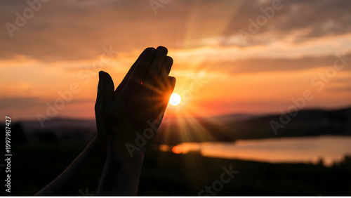 Silhouette of Hands in Prayer During a Golden Sunrise