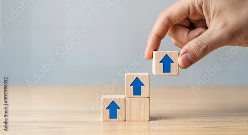 hand placing wooden block with blue arrow on top of stack