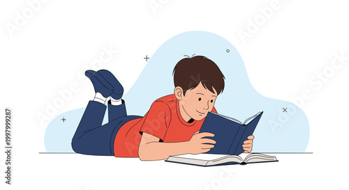 Focused young boy lies on the floor while reading an interesting book during his free time in a quiet home environment.