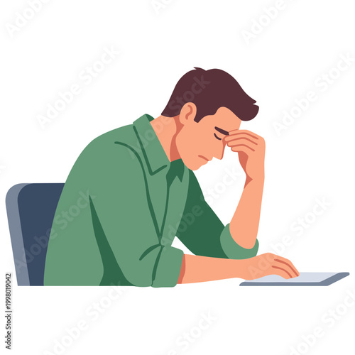 A man sits at a desk rubbing his eyes while working on a laptop with a concerned expression.