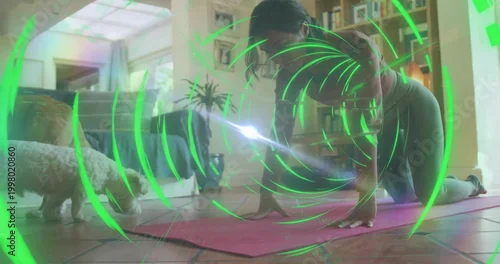 Obraz Stretching woman in leggings practicing at home, with pink mat, small dog, green holographic rings