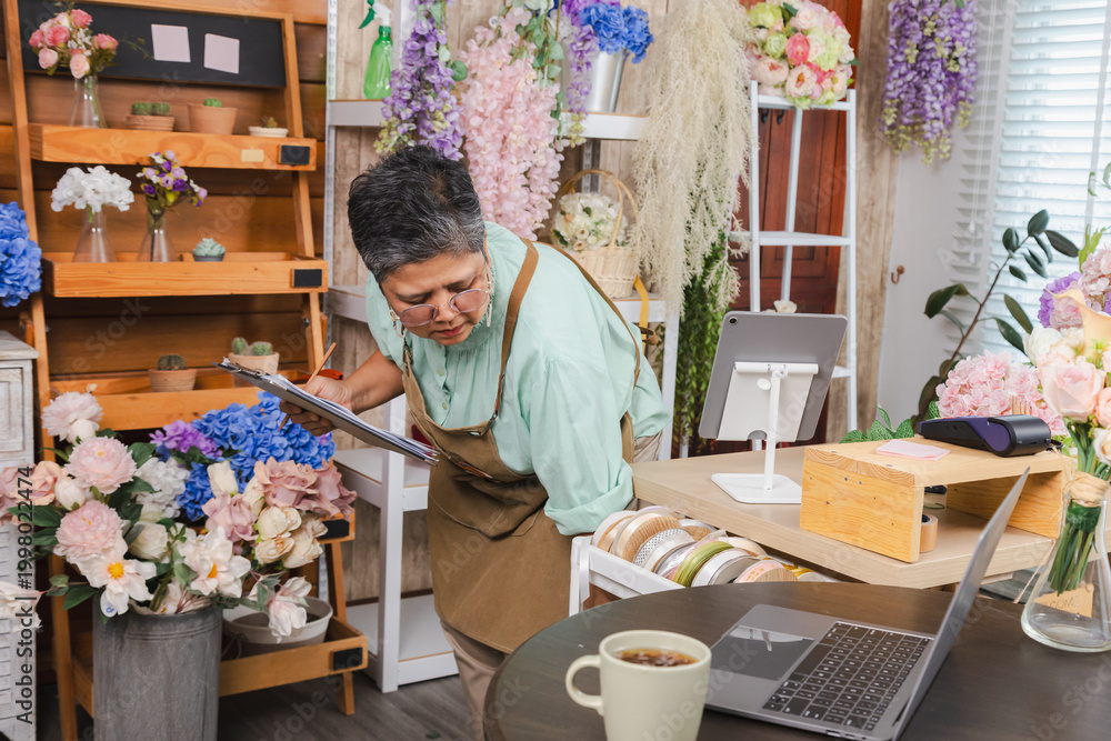 Fototapeta premium Asian senior woman, florist, small business owner, entrepreneur checking stock of decorative flowers in shop, showing independent business lifestyle, creative workspace, passion, and customer service