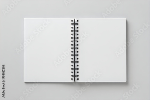 Open spiral notebook with blank white pages on a light gray background down view