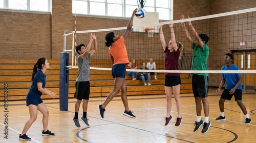 Group of students playing volleyball indoors in a gymnasium  