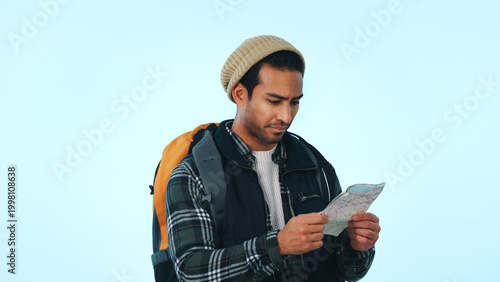 Fotografía Man, hiker and backpack with map in studio for location or lost direction on a blue background