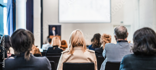 Speaker giving a talk in conference hall at business event. Rear view of unrecognizable people in audience at the conference hall. Business and entrepreneurship concept