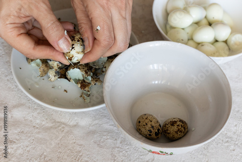 Woman peeling boiled quail eggs in kitchen, closeup