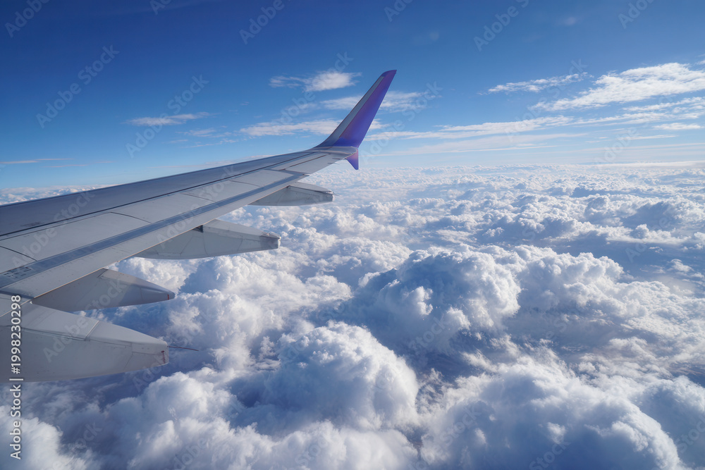 Fototapeta premium View from airplane wing over dense clouds during daylight sky