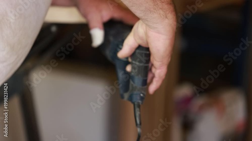 Hand using jigsaw cutting wood closeup with power tool during woodworking process indoor detail
