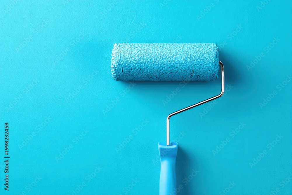 Fototapeta premium Using a paint roller on a smooth blue surface to apply fresh paint at a home improvement project