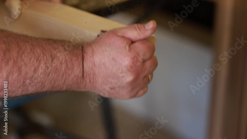 Man hand sanding wood after cutting closeup with fine dust in woodworking process indoor detail
