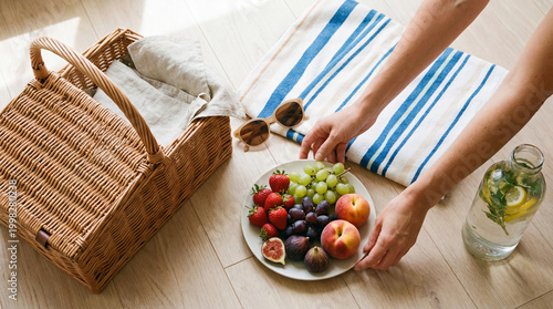 Women's hands put picnic fruit in the basket. Top view
