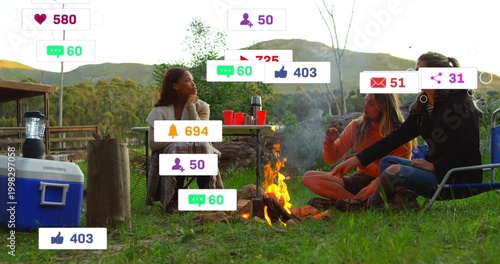 Gathering three friends wearing scarf and orange top around campfire at campsite, cooler, icons