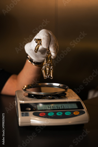 Фотография Jeweler weighing gold chain on precision scale to determine exact value