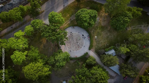 Cinematic aerial drone footage of Kaisaniemi Park dance pavilion on a beautiful sunny day. People enjoying outdoor dancing in a lively park atmosphere surrounded by greenery in Helsinki, Finland.