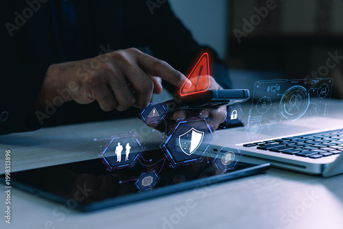 Foto User using smartphone with cybersecurity warning, shield and lock icons beside laptop, concept of mobile data protection and online threat detection