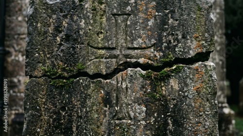 Ancient weathered stone cross with horizontal crack and moss growth.