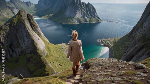 Scenic travel footage of a woman standing on a rocky mountain trail, looking over a dramatic fjord, steep peaks and turquoise water on a clear summer morning