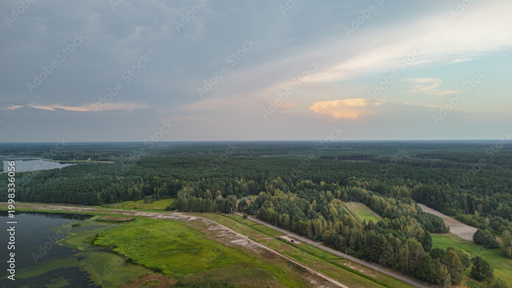 Fototapeta premium Aerial view of serene landscape showcasing sprawling forests, meandering rivers, and open fields. Soft sunset light creates a tranquil atmosphere, perfect for nature-related projects.