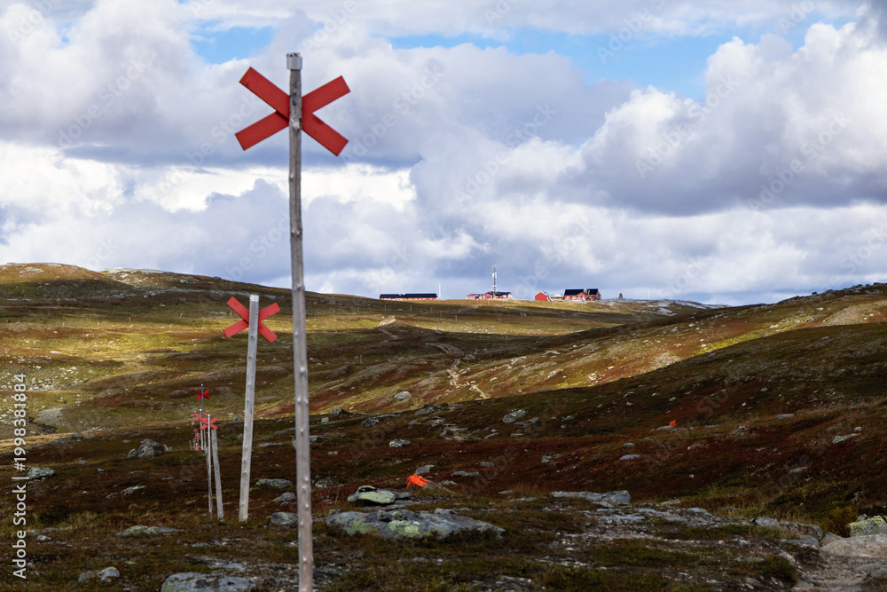 Fototapeta premium Swedish hiking trail signs and Blåhammaren mountain station on the horizon.