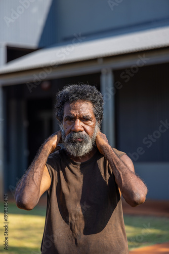 middle aged Aboriginal man standing outside wearing a grubby singlet