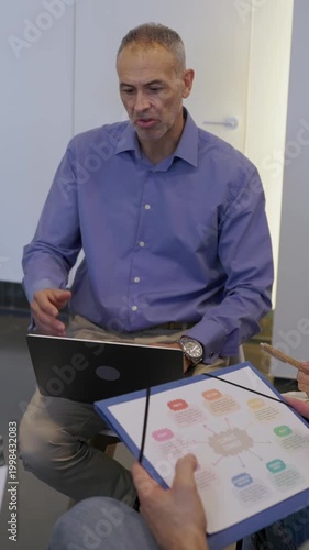 Vertical HD video of coworkers engaged in active debate during an informal meeting at the office. Multicultural professionals exchanging viewpoints and discussing solutions in a relaxed environment