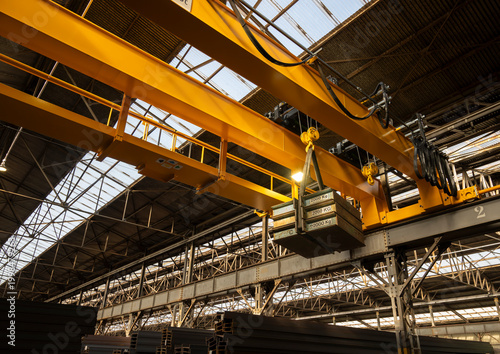 Canvas Print Heavy load suspended from overhead crane during industrial lifting operation