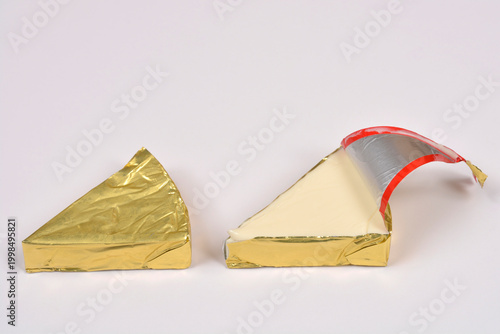 Schilderij op canvas A side view of two triangular processed cheese portions wrapped in gold foil wit