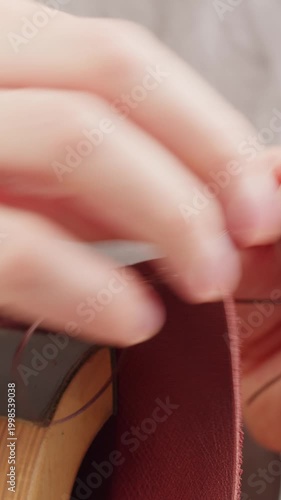 Man tailor repairing belt, artificial leather close-up. Craftsman making accessories made of genuine animal leather at workplace table. Professional atelier.