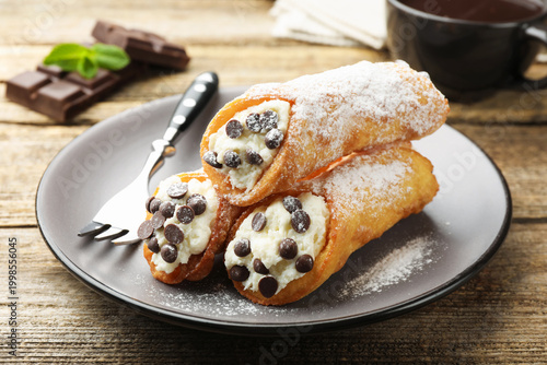Cuadro en lienzo Delicious cannoli with cheese, chocolate, powdered sugar, mint and coffee on woo