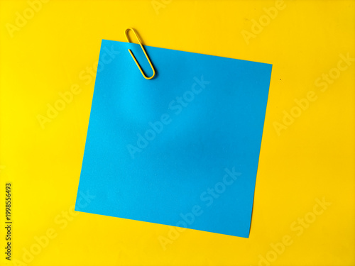 A bright blue paper note is centered on a vivid yellow background. 
