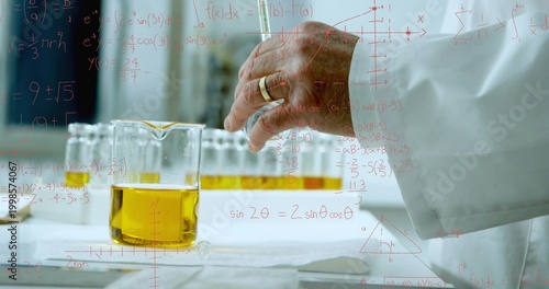 Reaching senior chemist handling glass beaker on lab bench, wearing white lab coat and gold ring